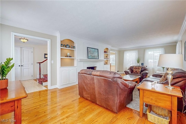 living area featuring light wood-type flooring, a fireplace, and ornamental molding