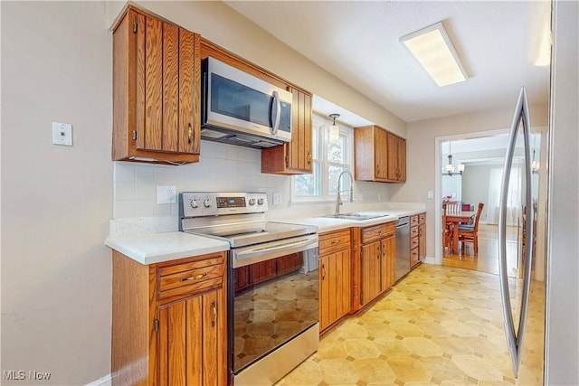 kitchen featuring appliances with stainless steel finishes, brown cabinetry, light countertops, and a sink