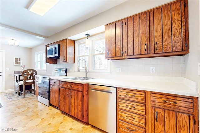 kitchen with a sink, stainless steel appliances, light countertops, and brown cabinets