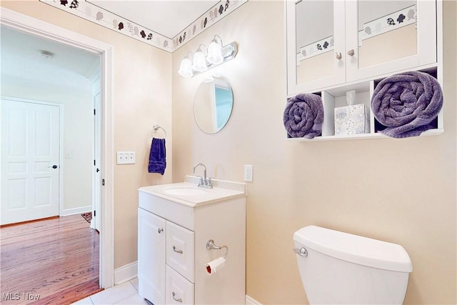 bathroom with tile patterned flooring, baseboards, vanity, and toilet