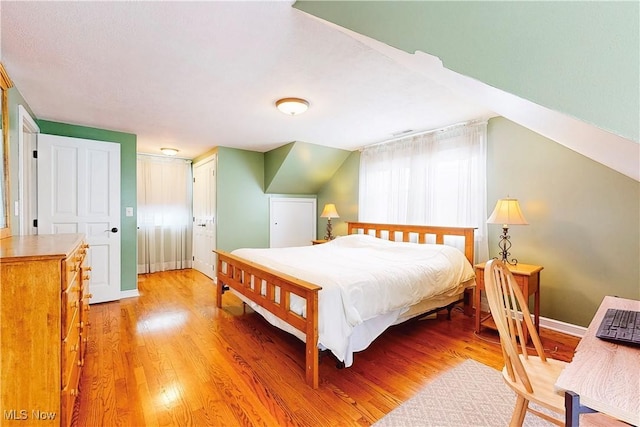 bedroom featuring baseboards, vaulted ceiling, and wood finished floors