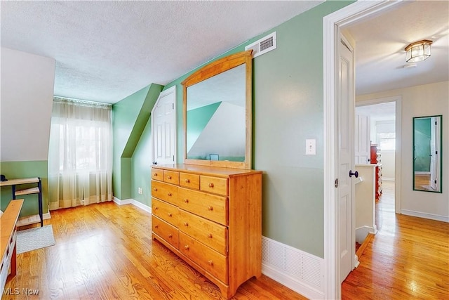 bedroom with a textured ceiling, light wood finished floors, and visible vents