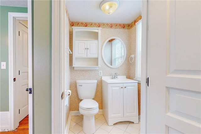 half bath with toilet, vanity, and wallpapered walls