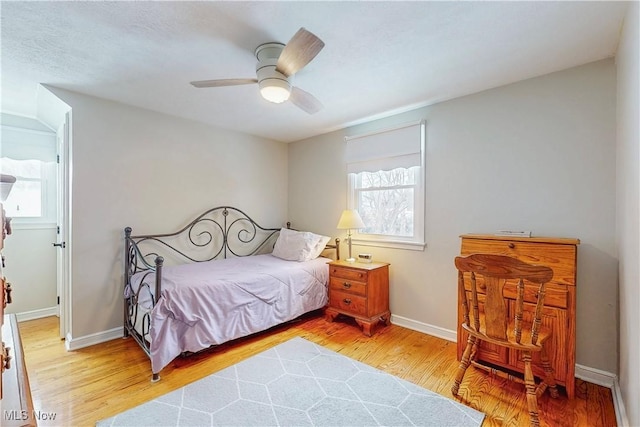 bedroom with a ceiling fan, light wood-style flooring, and baseboards