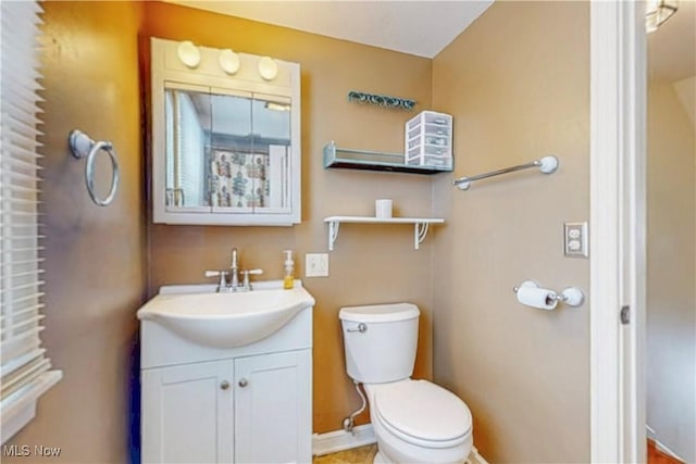 half bathroom with toilet, vanity, and baseboards