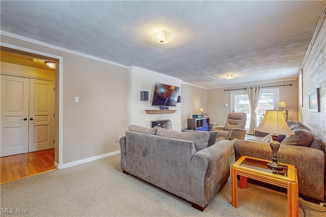 living area featuring ornamental molding, a brick fireplace, carpet flooring, and baseboards