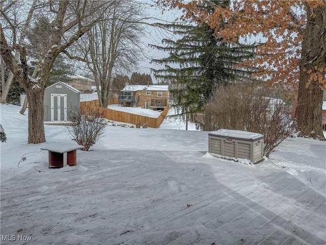 yard layered in snow featuring a storage shed and an outbuilding