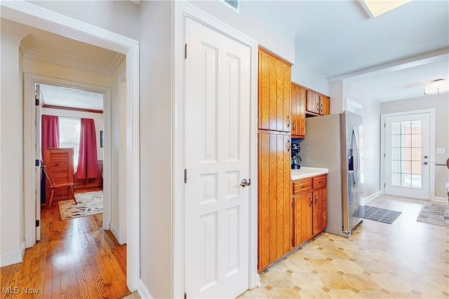 hallway featuring light wood-type flooring, baseboards, and ornamental molding