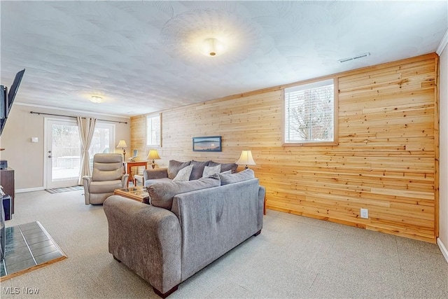 living area featuring light carpet, wood walls, a textured ceiling, and visible vents