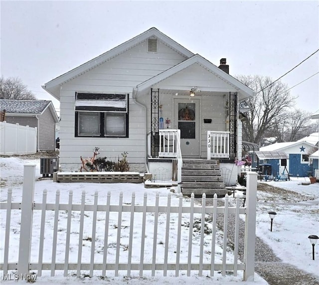 bungalow featuring cooling unit, fence, and a chimney