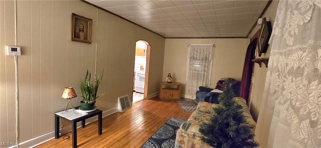 interior space with baseboards, visible vents, arched walkways, ornamental molding, and wood finished floors