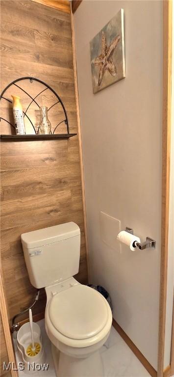 bathroom featuring wooden walls and toilet