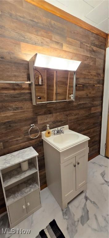 bathroom with marble finish floor, wood walls, and vanity