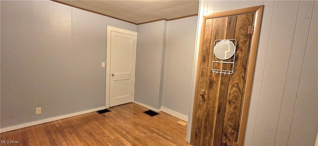 spare room featuring light wood-style flooring, visible vents, ornamental molding, and baseboards