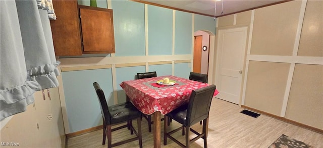 dining room with light wood-type flooring, visible vents, and arched walkways