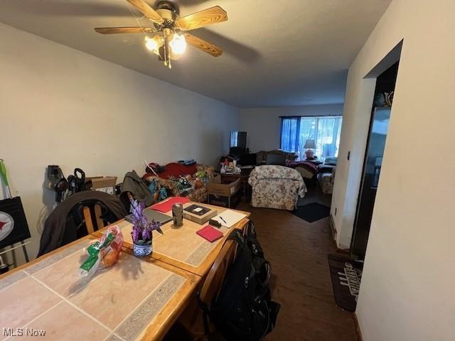 dining room with ceiling fan and dark colored carpet