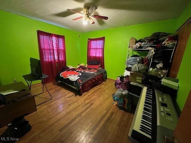 bedroom featuring ceiling fan, a textured ceiling, and wood finished floors