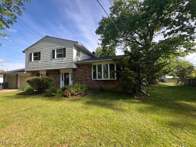 3335 N Maple Ln, Ashtabula, OH 44004 - view of front of house with a garage, a front lawn, and brick siding