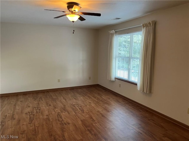 spare room with visible vents, baseboards, ceiling fan, and wood finished floors