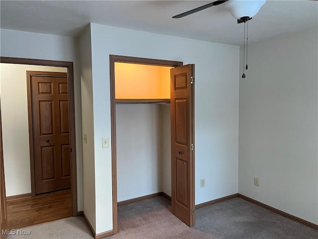 unfurnished bedroom featuring a ceiling fan, baseboards, a closet, and light colored carpet