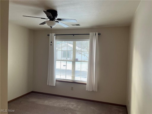 unfurnished room featuring carpet floors, baseboards, visible vents, and a ceiling fan