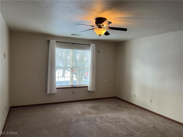 spare room with visible vents, a ceiling fan, light carpet, a textured ceiling, and baseboards