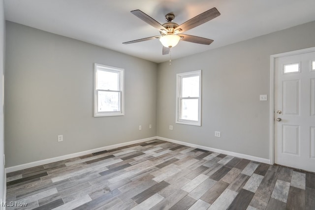 spare room featuring ceiling fan, light wood-type flooring, and baseboards