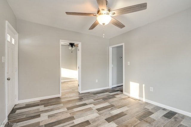 empty room featuring light wood-style floors, baseboards, and a ceiling fan