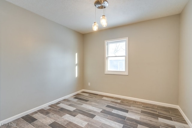 spare room with a textured ceiling, baseboards, and wood finished floors