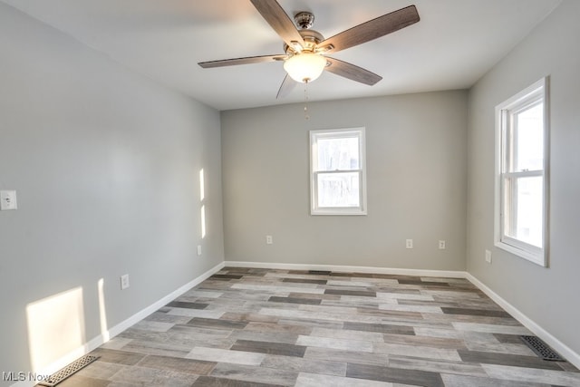 empty room with light wood-style floors, visible vents, baseboards, and ceiling fan