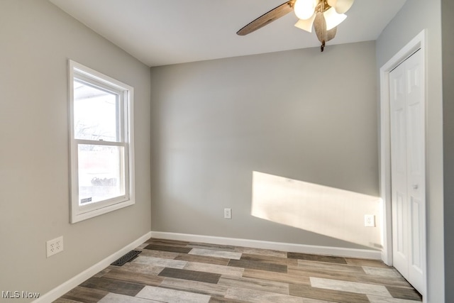 empty room featuring ceiling fan, light wood-style floors, visible vents, and baseboards