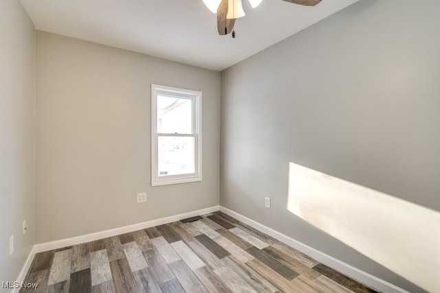 empty room featuring a ceiling fan, visible vents, baseboards, and wood finished floors