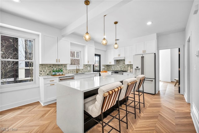 kitchen with decorative light fixtures, stainless steel appliances, light countertops, white cabinetry, and a kitchen island