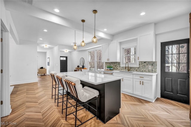 kitchen with pendant lighting, white cabinetry, light countertops, and a center island