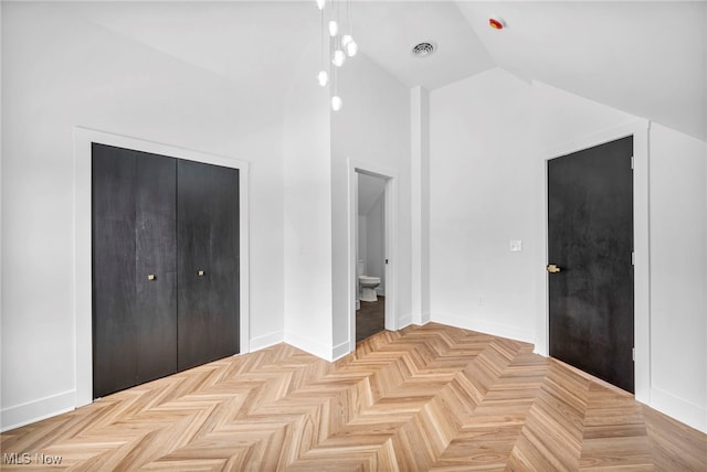 unfurnished bedroom with a closet, visible vents, connected bathroom, vaulted ceiling, and baseboards