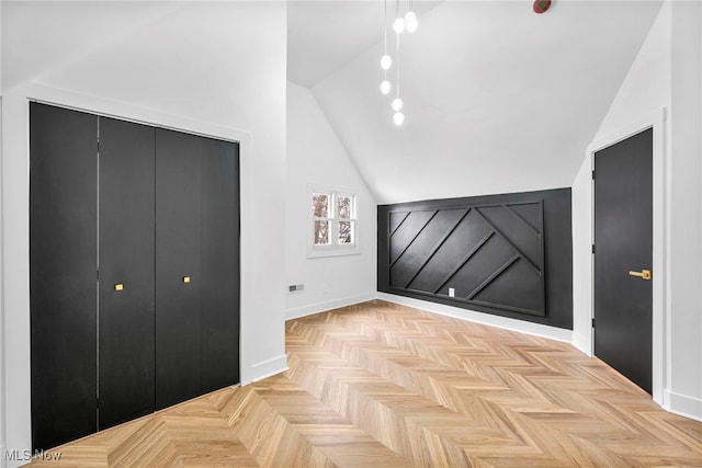 unfurnished bedroom with lofted ceiling, a closet, and baseboards