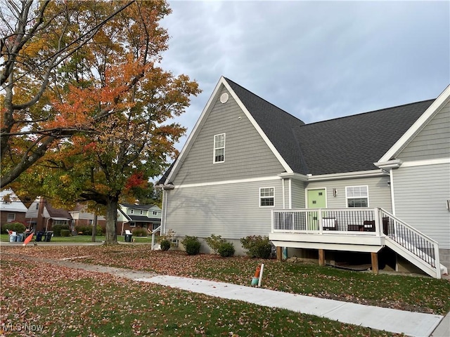 back of house with a shingled roof, a yard, and a deck