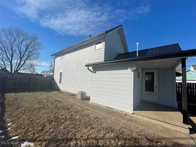 view of property exterior featuring fence, metal roof, and cooling unit