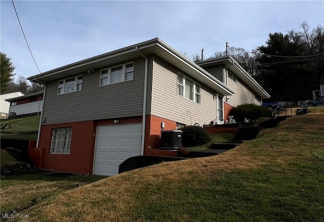 view of side of property with a garage, cooling unit, and a yard