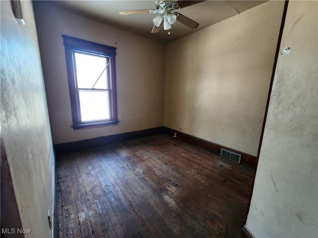 spare room featuring a ceiling fan, visible vents, baseboards, and hardwood / wood-style flooring