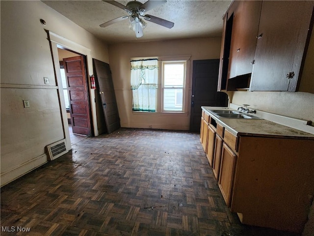 kitchen featuring a ceiling fan, a textured ceiling, visible vents, and a sink