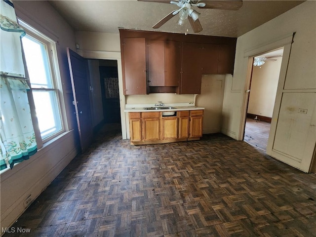 kitchen featuring light countertops, a sink, a textured ceiling, and ceiling fan