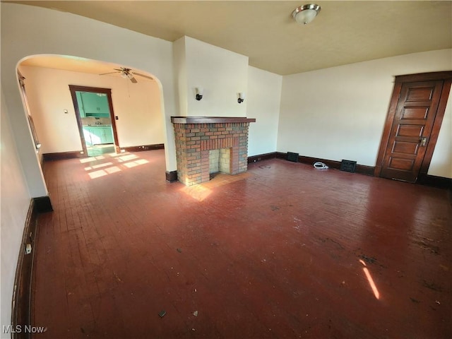 unfurnished living room with arched walkways, a fireplace, and wood-type flooring