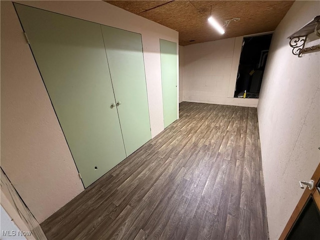 spare room featuring wood finished floors and concrete block wall