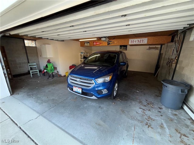 garage featuring concrete block wall and a garage door opener