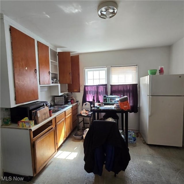 kitchen featuring brown cabinetry, light countertops, and freestanding refrigerator