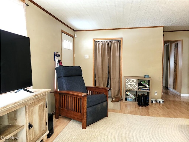 sitting room with ornamental molding and light wood-type flooring