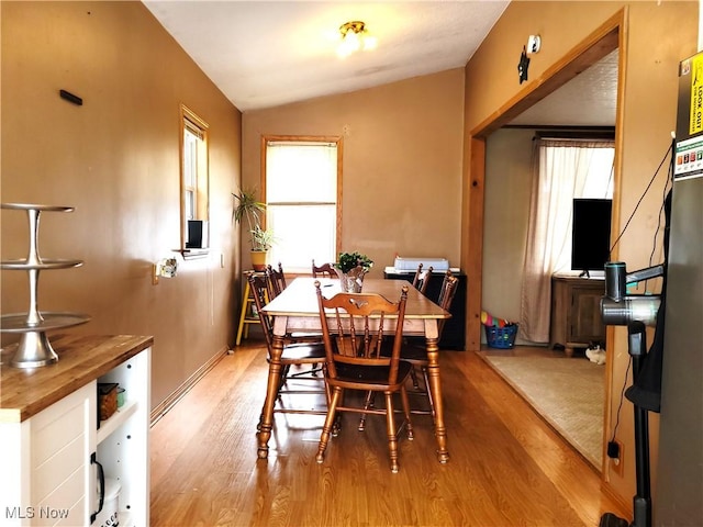 dining area featuring lofted ceiling and light wood finished floors