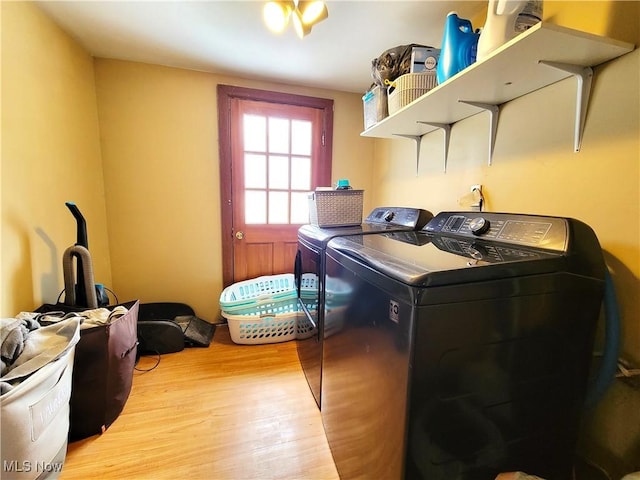 clothes washing area with laundry area, washing machine and dryer, and wood finished floors