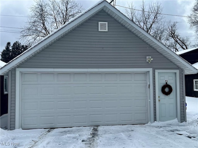 snow covered garage featuring a detached garage